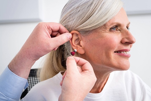 Ältere Frau erhält ein modernes Hörgerät zur Verbesserung ihres Hörvermögens.